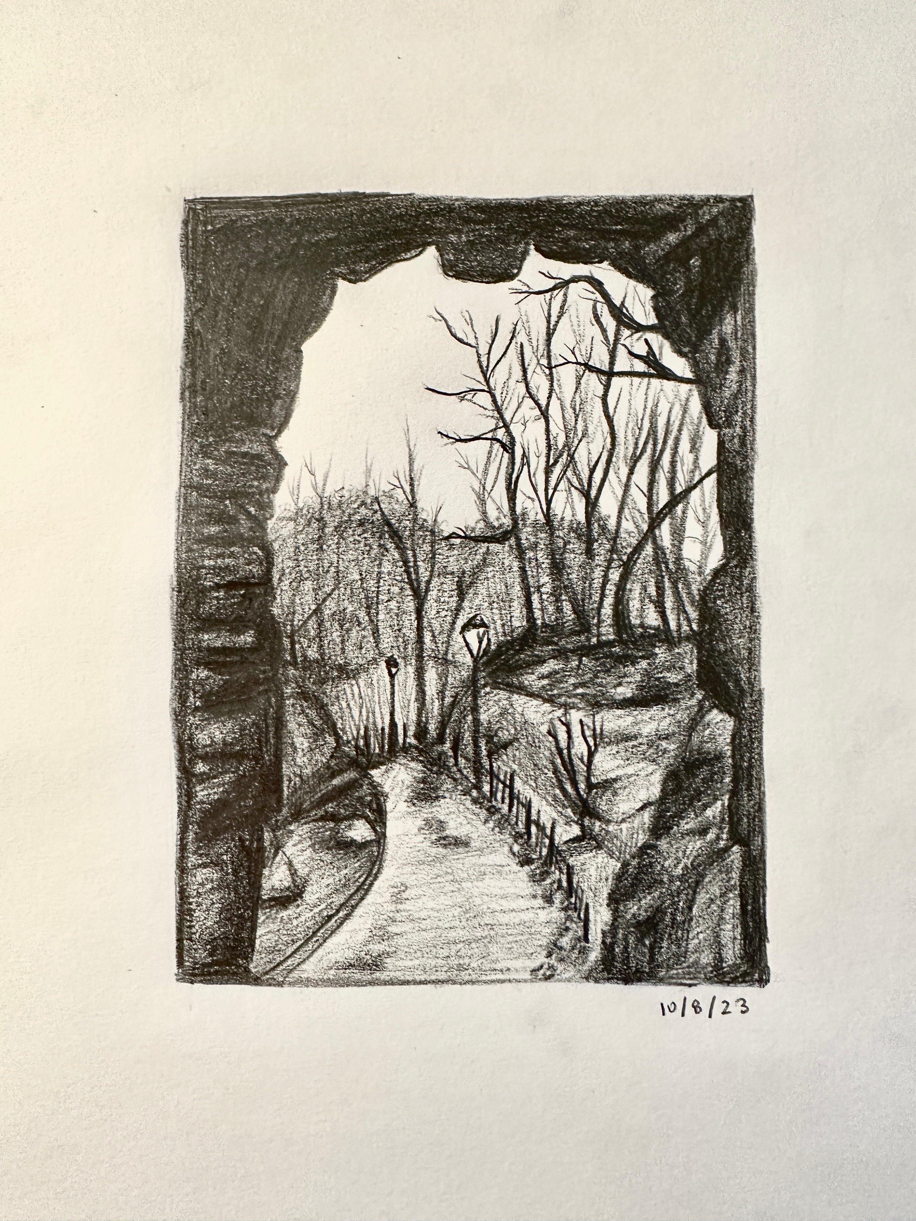 You stand under a bridge, looking out onto a path leading somewhere in a dark forest. Streetlamps light your way.